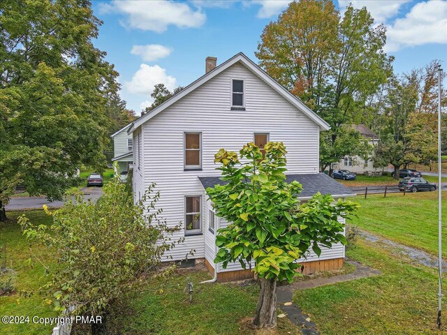 view of side of property featuring a chimney and a yard