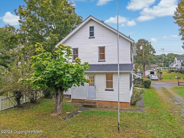 back of house featuring a shingled roof, a lawn, entry steps, fence, and driveway