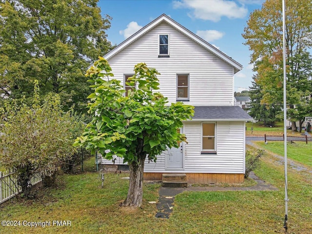 rear view of property featuring entry steps and a yard