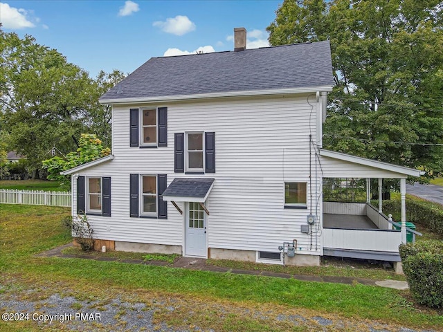 rear view of property with a shingled roof, fence, a chimney, and a lawn