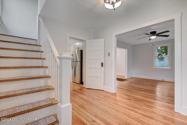 staircase featuring ceiling fan, baseboards, and wood finished floors