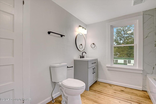 full bath with visible vents, toilet, a bathing tub, wood finished floors, and vanity