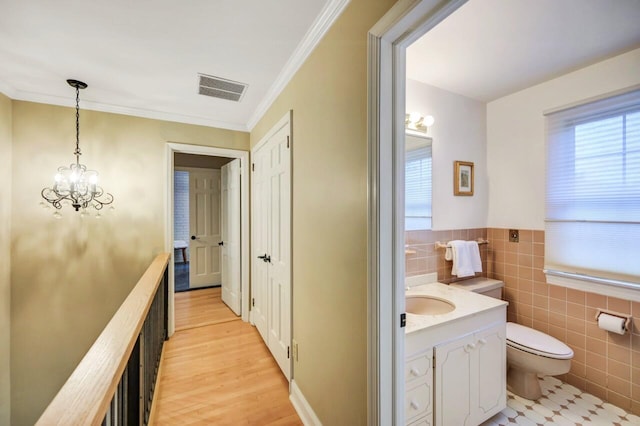938 Meadow Cir, Bethlehem, PA 18017 - hall featuring tile walls, a chandelier, light wood-style flooring, crown molding, and wainscoting