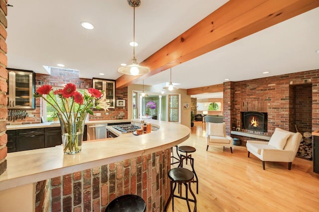 938 Meadow Cir, Bethlehem, PA 18017 - kitchen featuring appliances with stainless steel finishes, light countertops, light wood finished floors, a kitchen bar, and a brick fireplace
