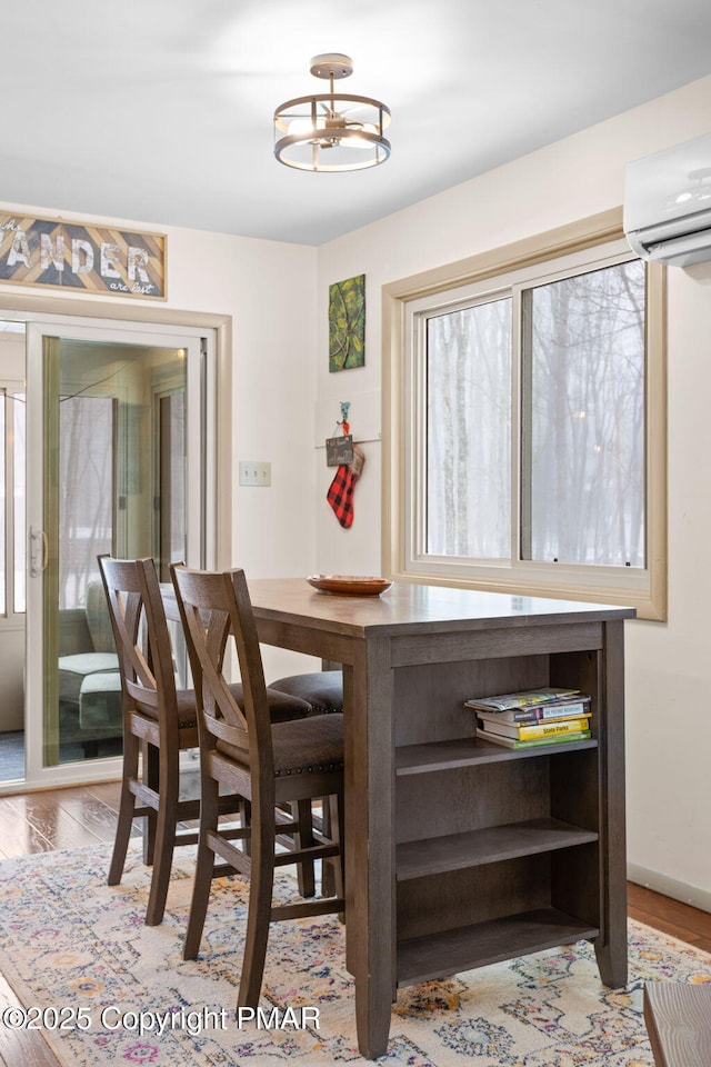 dining area featuring a wall unit AC and wood finished floors