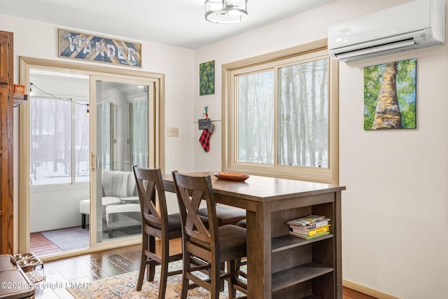 dining room with an AC wall unit and wood finished floors