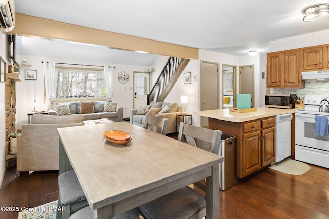 kitchen with under cabinet range hood, white appliances, dark wood-type flooring, open floor plan, and backsplash