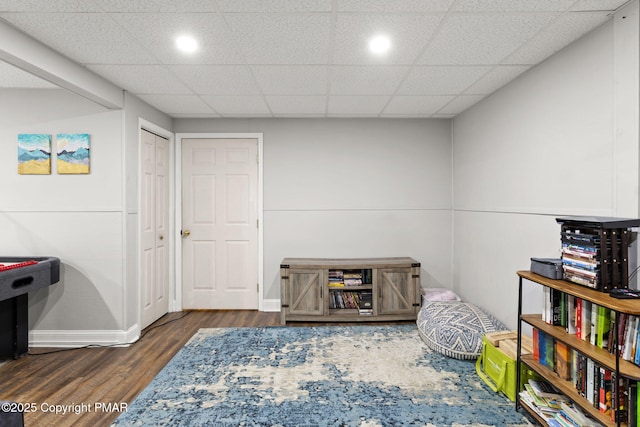 playroom featuring a paneled ceiling, baseboards, and wood finished floors