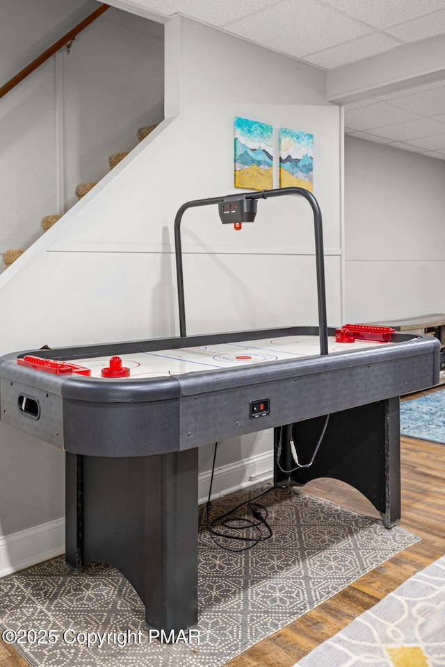 playroom with wood finished floors, a paneled ceiling, and baseboards