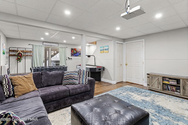 living area featuring a paneled ceiling, baseboards, wood finished floors, and recessed lighting