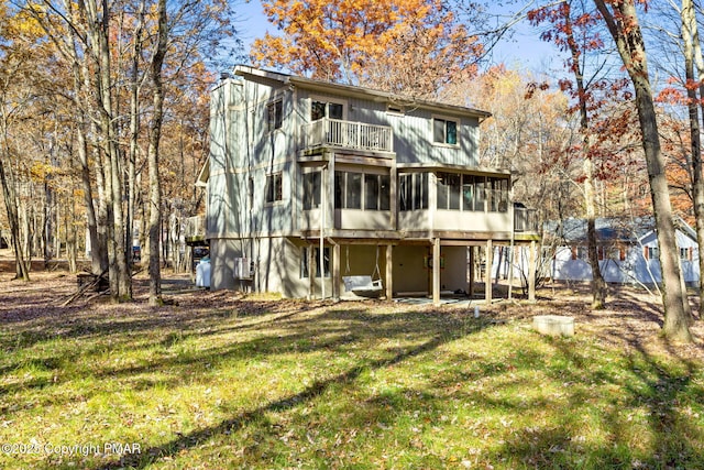 back of property with a balcony, a sunroom, and a lawn