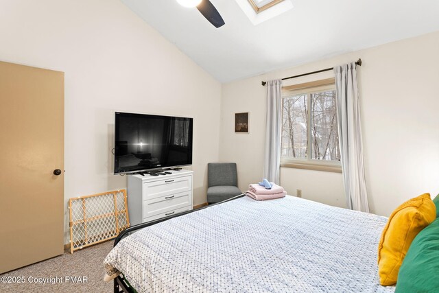 carpeted bedroom featuring lofted ceiling with skylight and ceiling fan