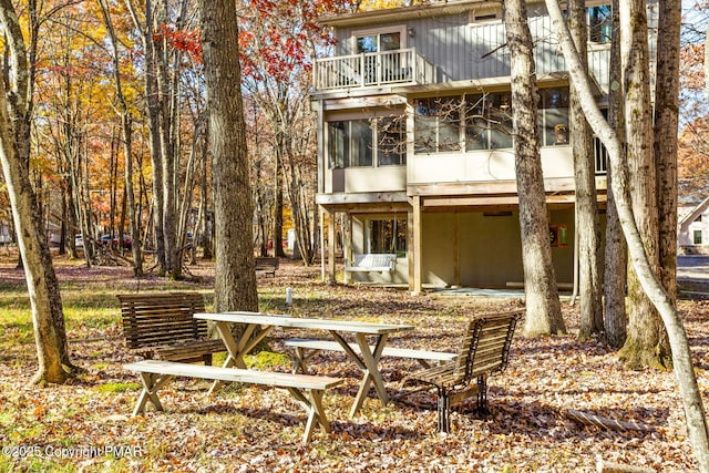 rear view of property with a sunroom and a balcony