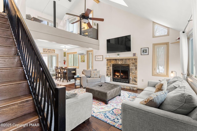 living area featuring dark wood-style flooring, a healthy amount of sunlight, stairway, and a stone fireplace