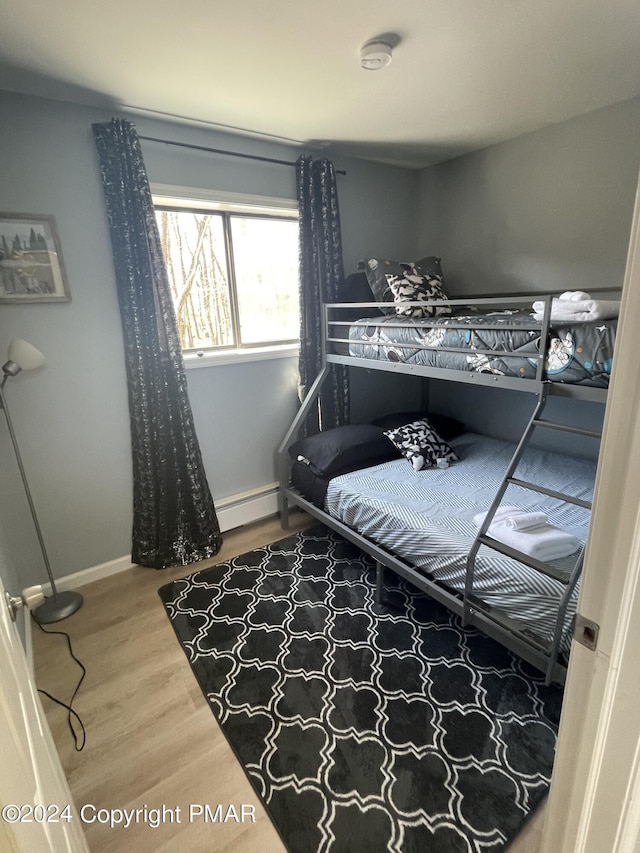 bedroom featuring baseboards, wood finished floors, and baseboard heating