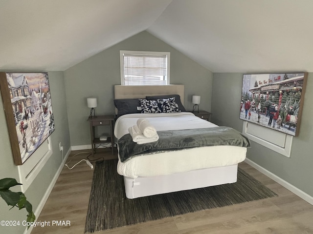 bedroom with baseboards, wood finished floors, and lofted ceiling