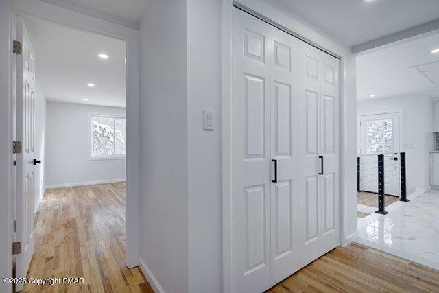 hall featuring recessed lighting, baseboards, and light wood-type flooring