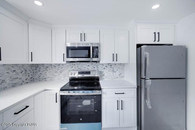 kitchen with decorative backsplash, appliances with stainless steel finishes, white cabinetry, and light countertops