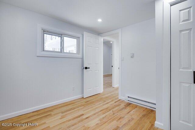 empty room featuring recessed lighting, baseboards, baseboard heating, and light wood-style flooring