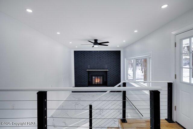 stairway with hardwood / wood-style flooring, ceiling fan, and a fireplace