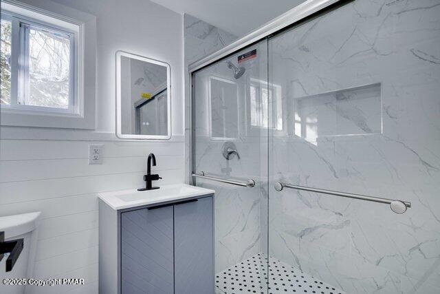 full bathroom featuring vanity, toilet, and a marble finish shower