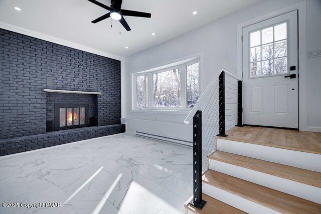 entrance foyer featuring marble finish floor, a brick fireplace, a baseboard heating unit, and ceiling fan