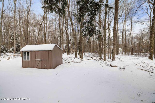 snowy yard featuring an outdoor structure and a shed