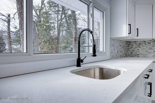 kitchen featuring white cabinets, plenty of natural light, and light stone countertops