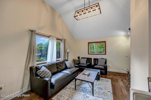 living area with plenty of natural light, wood finished floors, baseboards, and vaulted ceiling