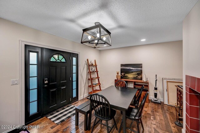 dining room with a notable chandelier, a textured ceiling, baseboards, and hardwood / wood-style flooring