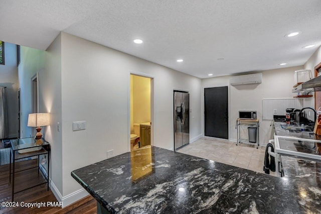 kitchen with baseboards, dark stone counters, recessed lighting, appliances with stainless steel finishes, and a textured ceiling