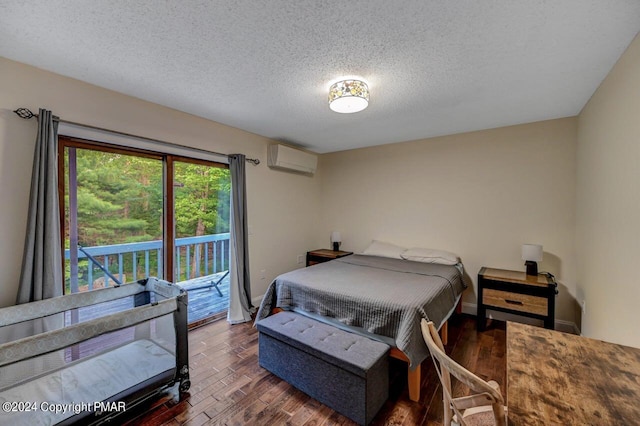 bedroom featuring a textured ceiling, access to exterior, wood finished floors, and a wall mounted AC