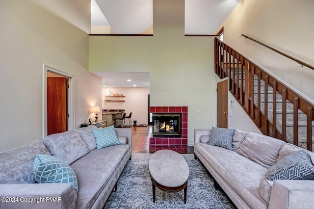 living area featuring stairway, a high ceiling, wood finished floors, and a tile fireplace