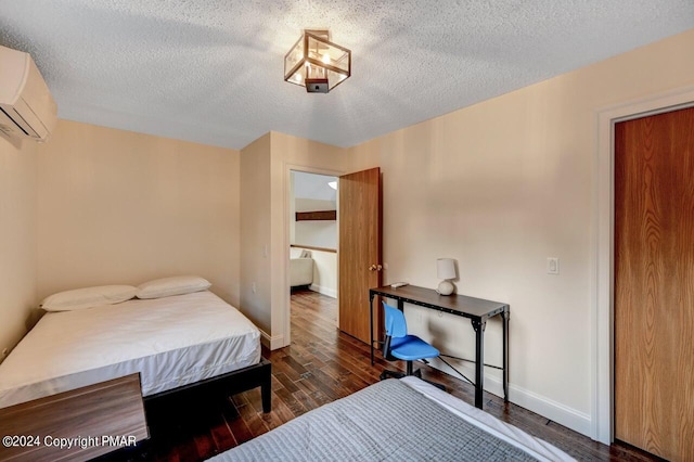 bedroom with a textured ceiling, wood finished floors, baseboards, and a wall mounted AC