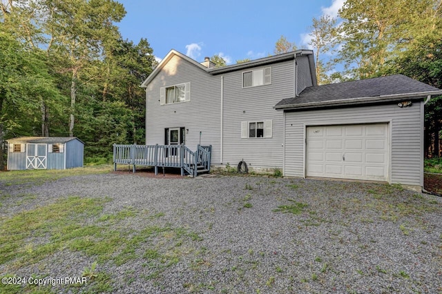 rear view of property with an outbuilding, a deck, a storage shed, an attached garage, and a chimney