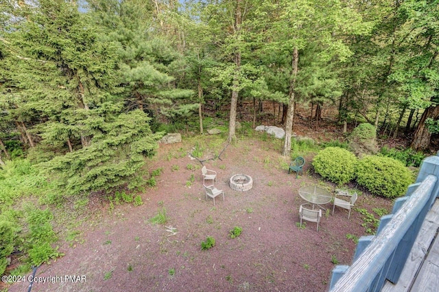 view of yard featuring a fire pit and a view of trees