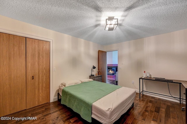 bedroom with a closet, a textured ceiling, baseboards, and wood-type flooring