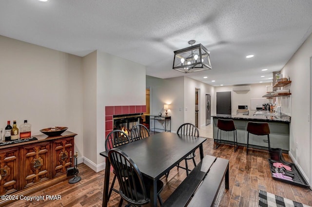 dining space featuring a tiled fireplace, baseboards, wood-type flooring, and a wall mounted AC