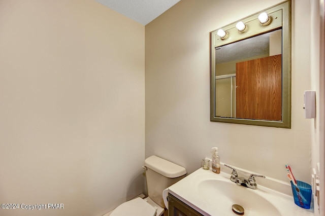 bathroom with a textured ceiling, toilet, and vanity