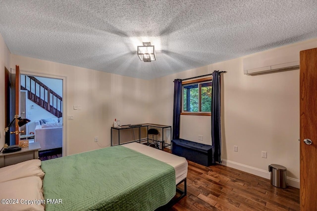 bedroom with baseboards, a textured ceiling, an AC wall unit, and wood finished floors