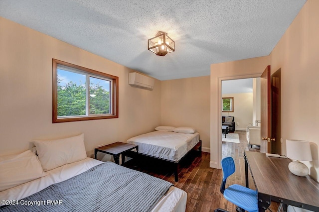 bedroom with dark wood finished floors, a textured ceiling, an AC wall unit, and baseboards