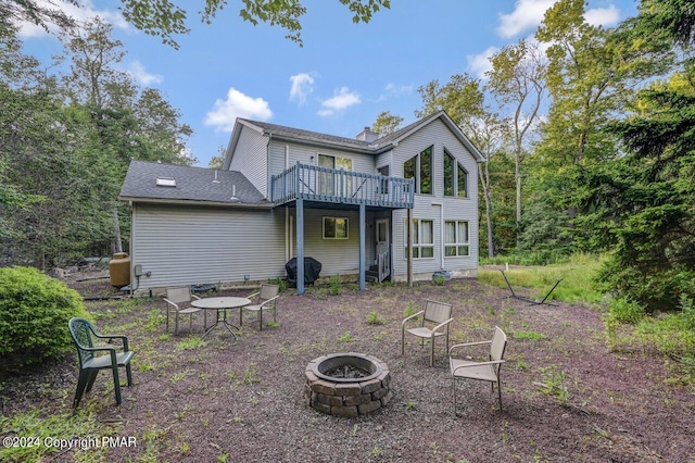 rear view of property with a wooden deck, a chimney, and an outdoor fire pit