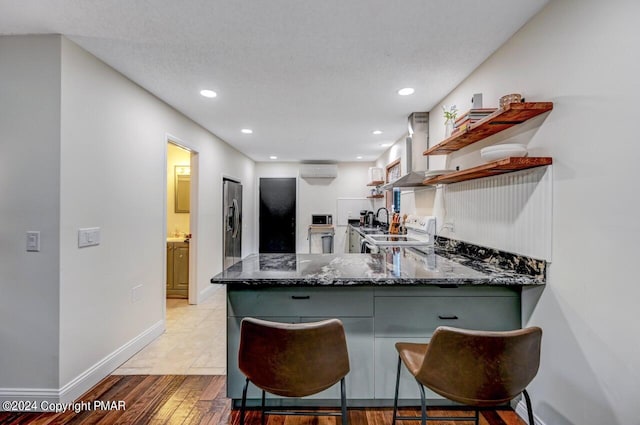 kitchen with ventilation hood, white range with electric cooktop, dark stone counters, a peninsula, and open shelves