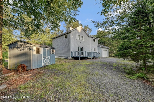 view of home's exterior featuring a garage, an outdoor structure, a chimney, and a shed