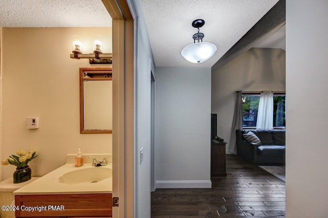 bathroom featuring a textured ceiling, vanity, baseboards, and hardwood / wood-style flooring