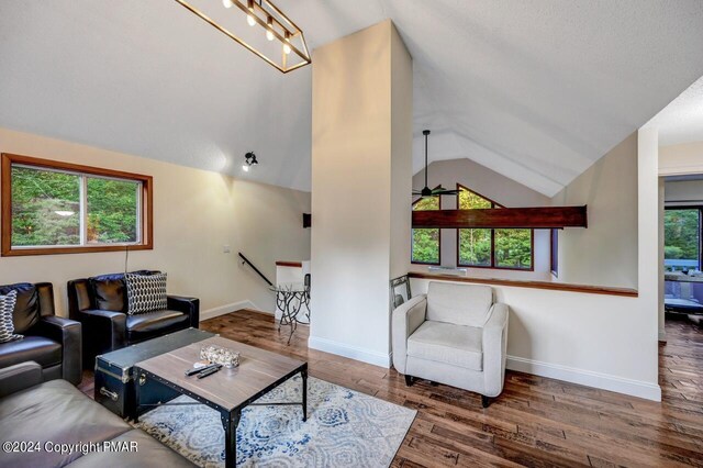 living area with a ceiling fan, vaulted ceiling, wood finished floors, and baseboards