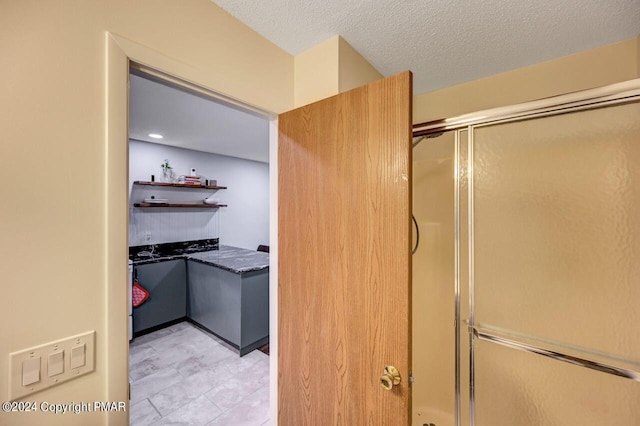 full bath featuring a textured ceiling and a shower with shower door