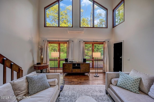 living room with an AC wall unit, a high ceiling, and wood finished floors