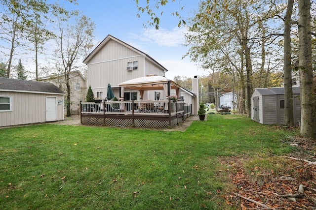 rear view of property featuring a shed, a wooden deck, a gazebo, a lawn, and an outdoor structure