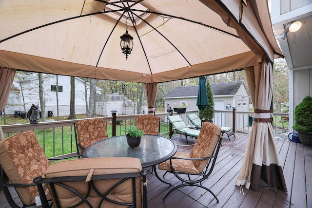 wooden terrace featuring outdoor dining space and a gazebo